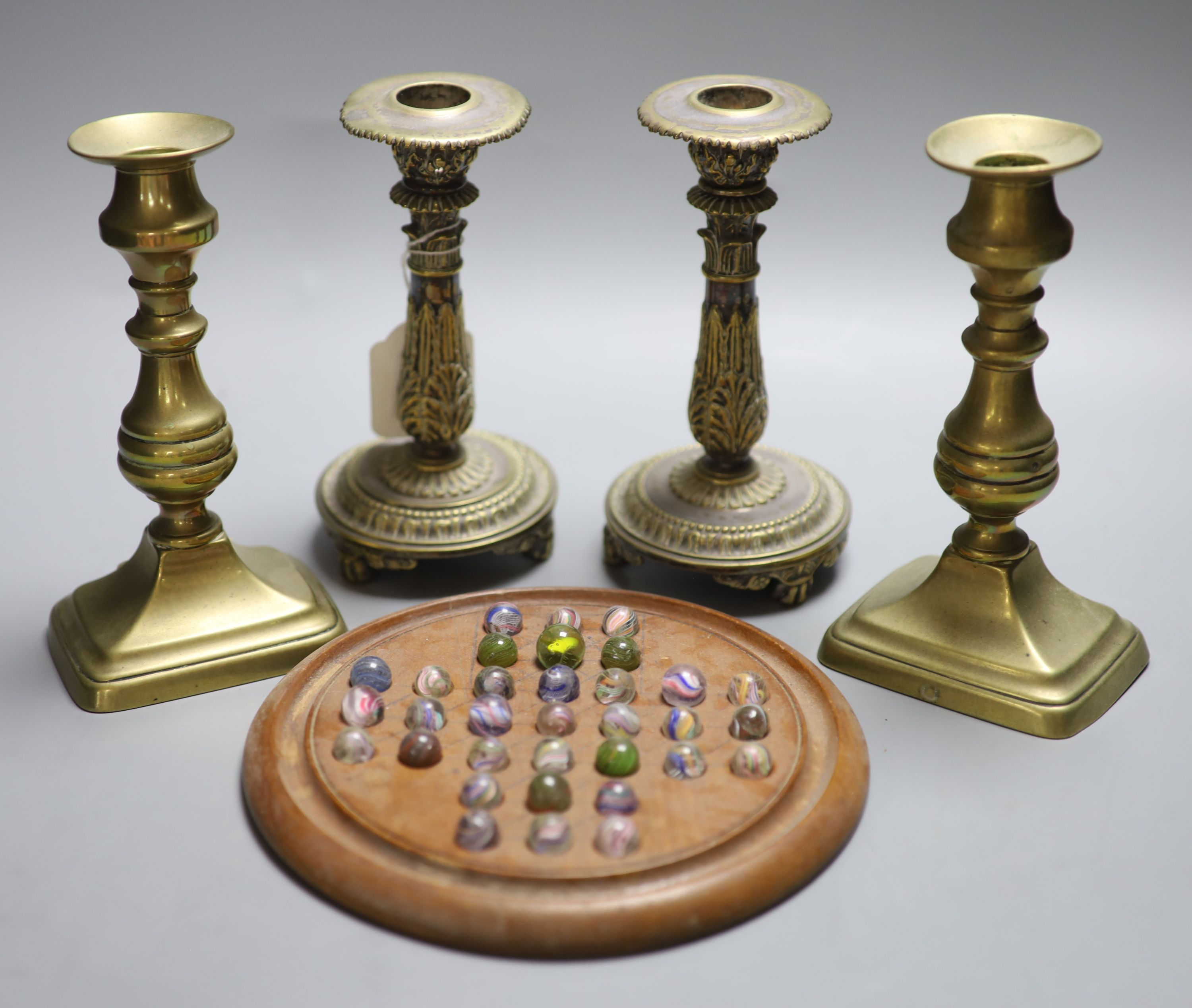 Two pairs of brass candlesticks and a solitaire board with marbles